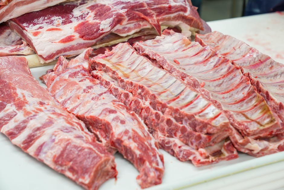 Close-up of fresh raw pork ribs neatly arranged on a cutting board, showcasing marbling.